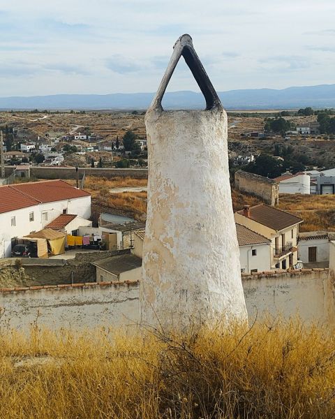 Archivo:Benamaurel, Granada, Región de Granada, España. Chimenea de una casa-cueva que sobresale por encima del monte que la resguarda en su interior..jpg
