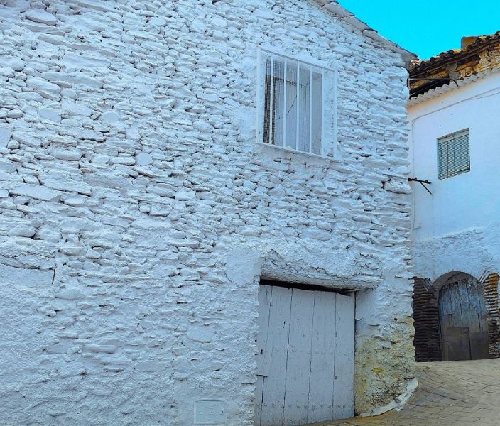 Archivo:Casa humilde de Huéneja, Granada, Región de Granada, realizada con mampostería al natural que en su origen no debió estar pintada. La casa del fondo, más señorial, conserva un hermoso arco escarzano..jpg
